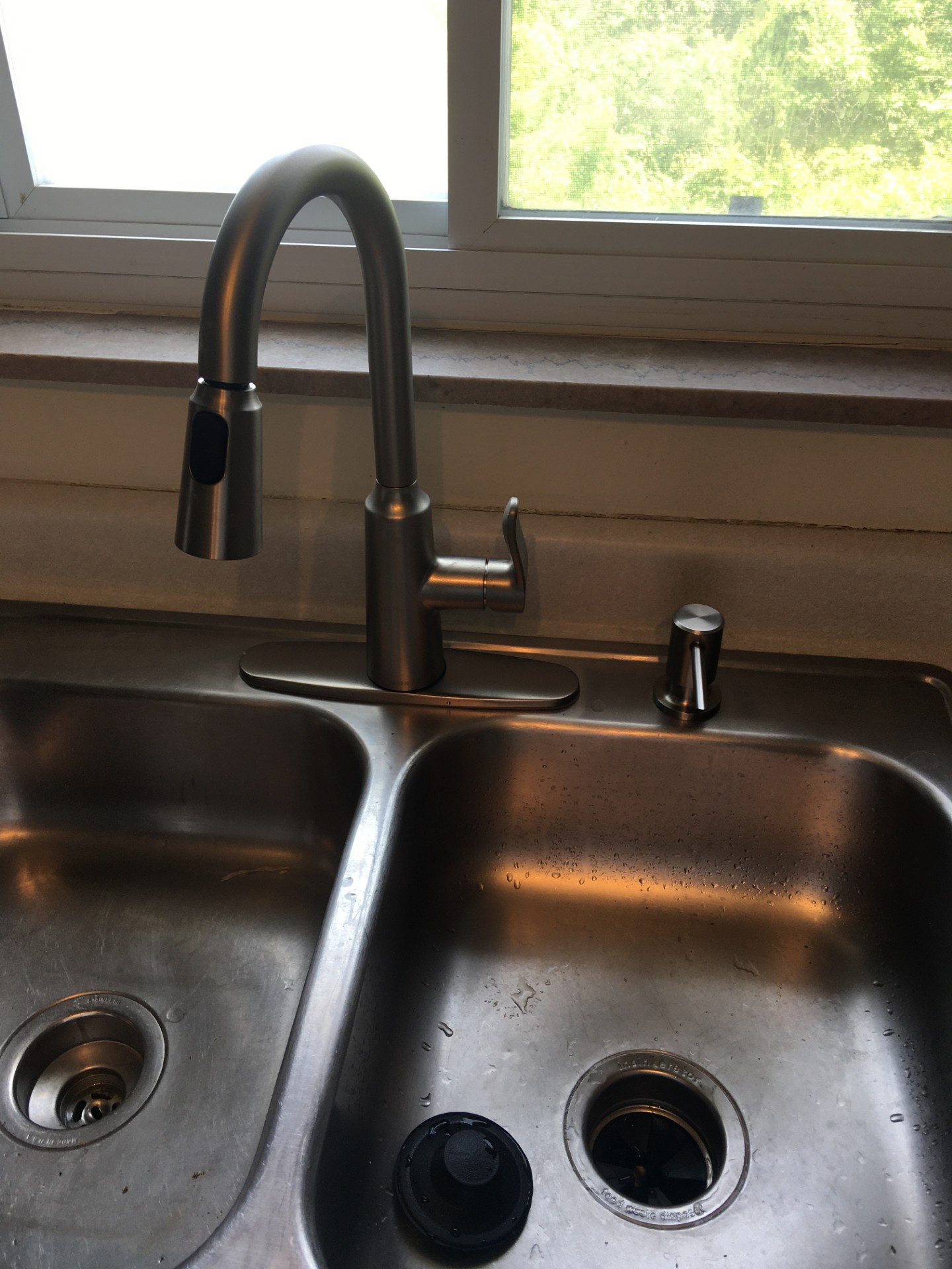 New pull-down kitchen faucet installed over a stainless steel sink